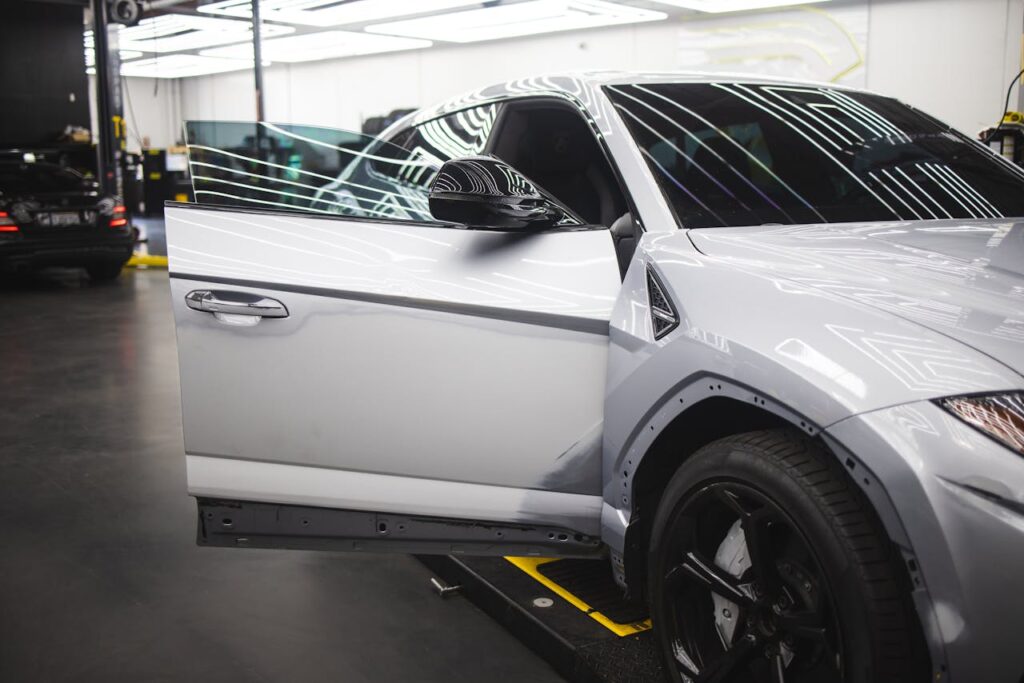 Luxury vehicle undergoing service in a well-lit auto repair shop, showcasing sleek design and glossy finish.