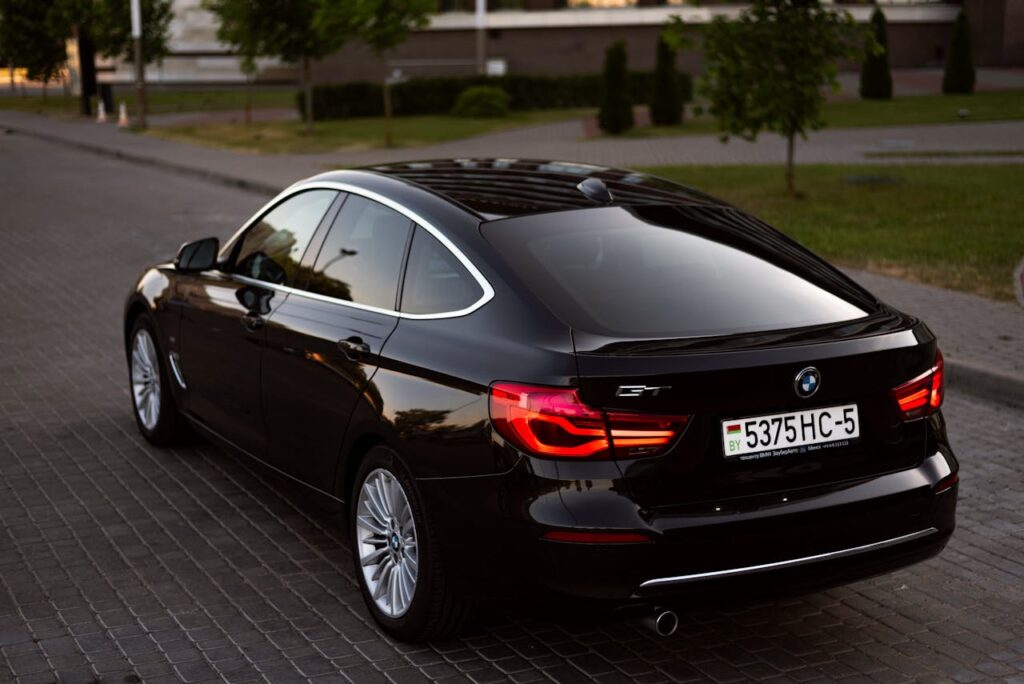 Sleek black BMW sedan parked on a cobblestone street in Minsk, Belarus at dusk.