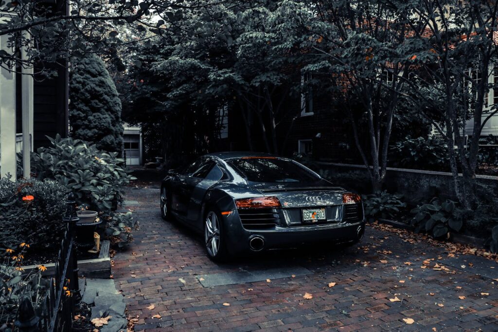 A sleek Audi R8 parked in a leafy residential driveway in Cape May, NJ, showcasing elegance and luxury.