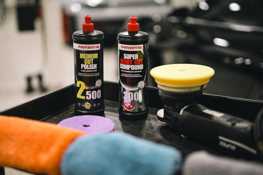 Image of car polishing products and a buffer in an auto garage setting.