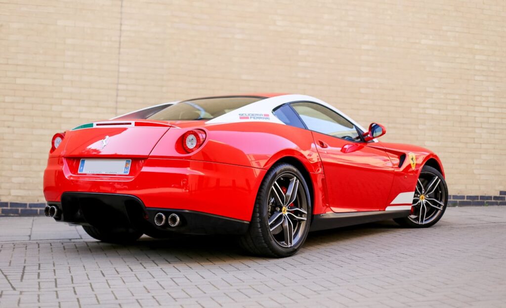 Rear view of a luxurious red sports car parked on a brick pavement showcasing its sleek design.