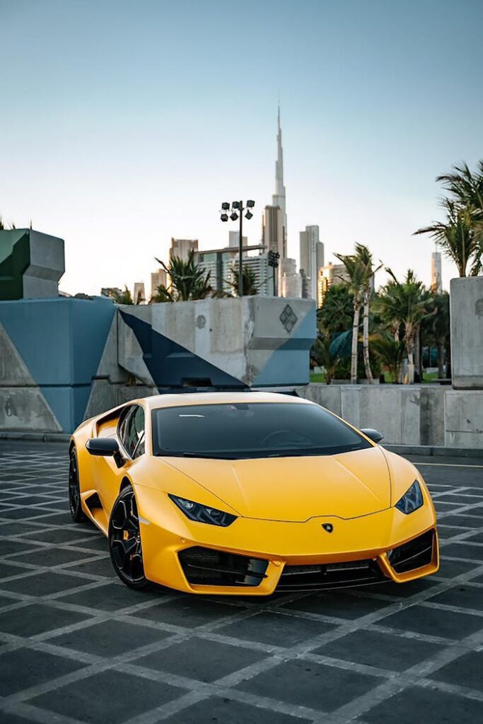 Stunning yellow Lamborghini parked with the Burj Khalifa in the background during the day.